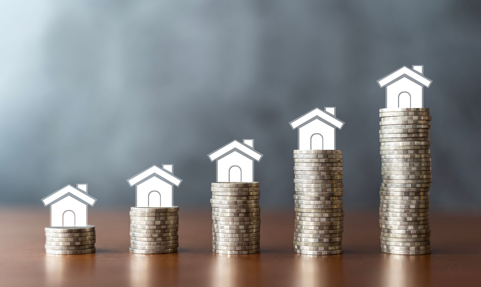 Maison blanche miniature sur des pièces empilées utilisant comme concept immobilier et financier. Idéal pour les échelles immobilières hypothécaires et les investissements immobiliers.